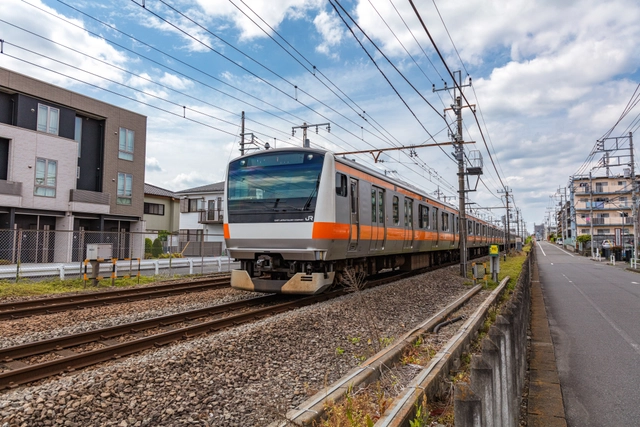 住宅街を走る青梅線のE233系｜東京都羽村市